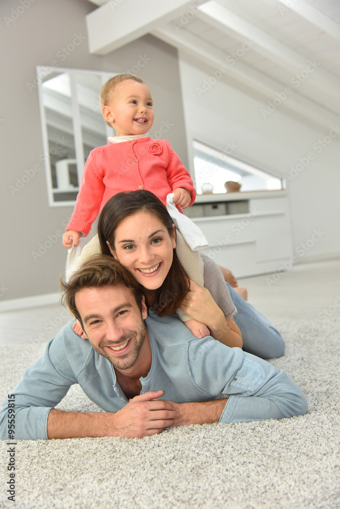 Obraz premium Parents and baby girl laying on carpet,