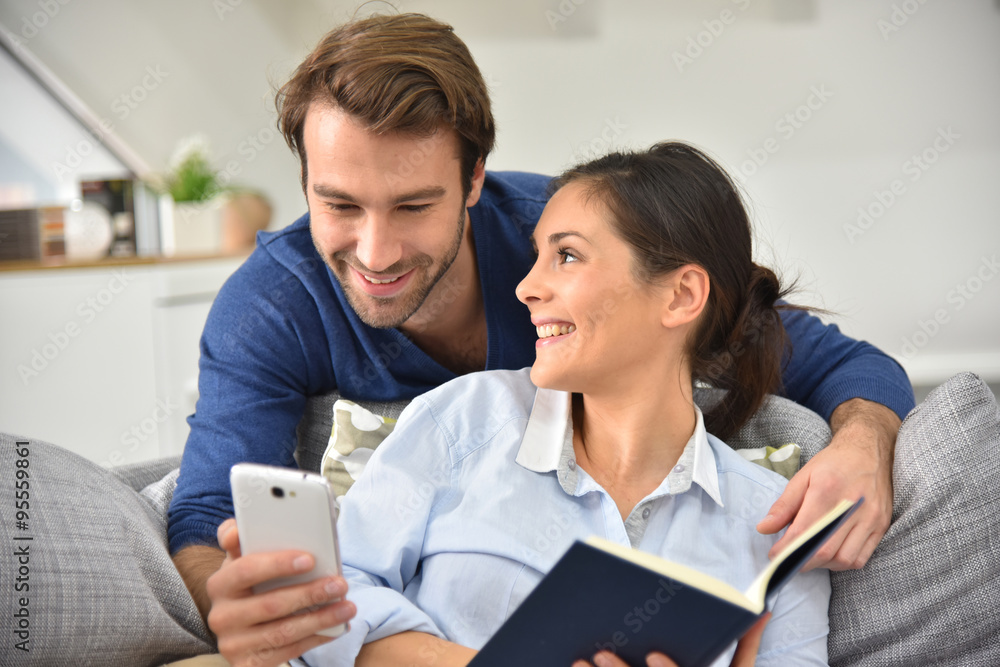 Couple at home entertaining and reading message on smartphone