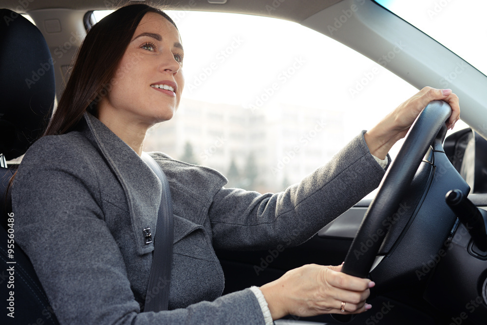 cheerful young woman driving a car