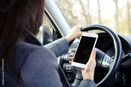 woman using smartphone and driving a car