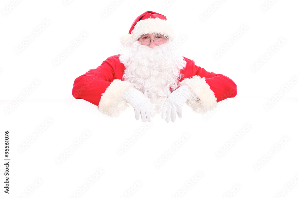 Kind Santa Claus looking out from behind the blank sign isolated on white background with copy space Kind Santa Claus looking out from behind the blank sign isolated on white background with copy space