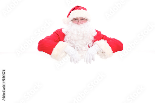 Kind Santa Claus looking out from behind the blank sign isolated on white background with copy space © rogerphoto