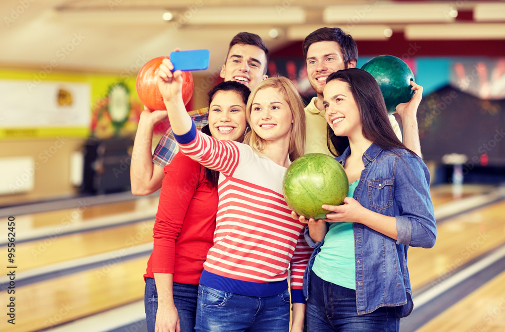 Fototapeta premium happy friends with smartphone in bowling club