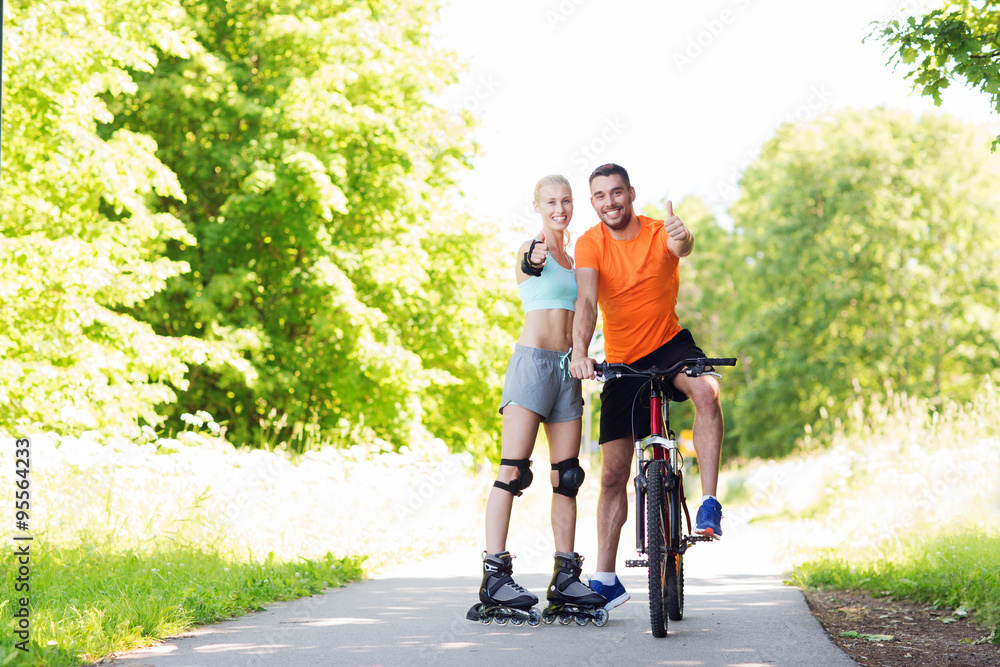 Fototapeta premium couple on rollerblades and bike showing thumbs up