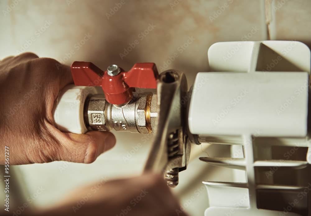 Close-up of mature mechanic hands repairing heating system. - obrazy, fototapety, plakaty 
