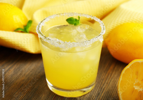 Glass of lemon juice on wooden table, closeup