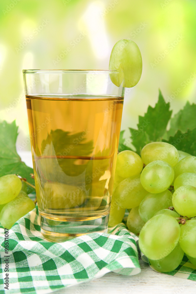 Glass of grape juice on table with checkered napkin on light blurred background Glass of grape juice on table with checkered napkin on light blurred background