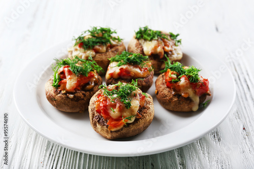 A plate with stuffed mushrooms on wooden background