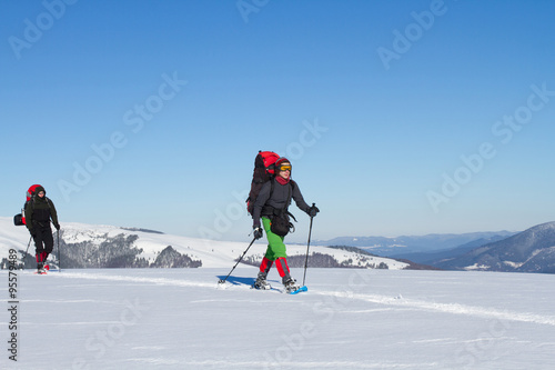 Winter hiking in the mountains on snowshoes with a backpack and tent.