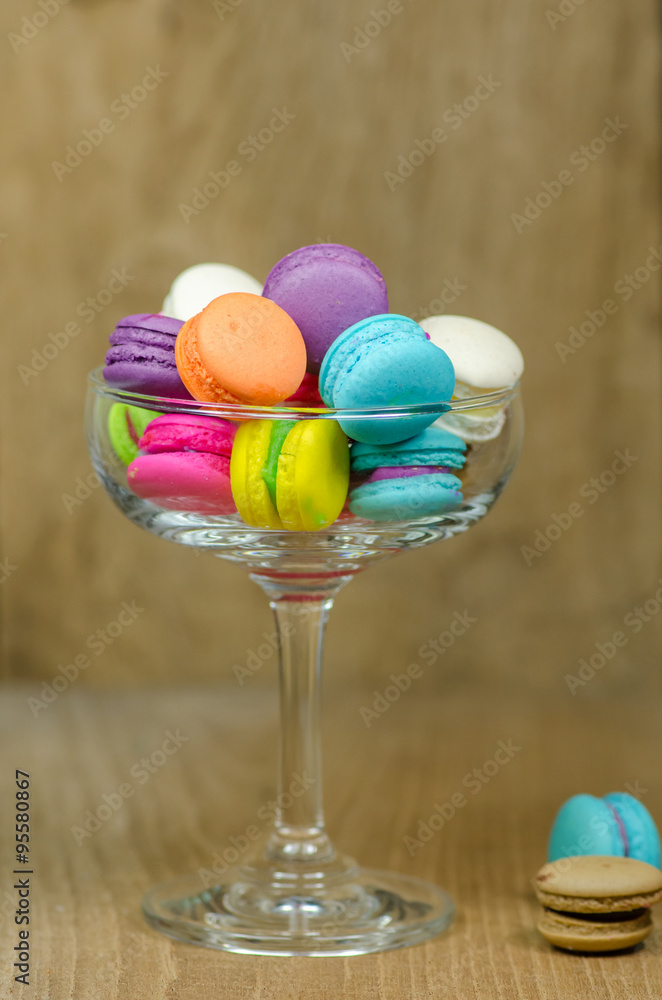 colorful macaroons in glass on wooden table colorful macaroons in glass on wooden table