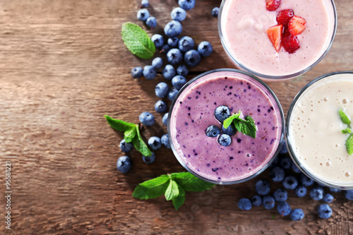 Fototapeta Naklejka Na Ścianę i Meble -  Tasty blueberry, strawberry and milk yogurts with berries and mint around on wooden background