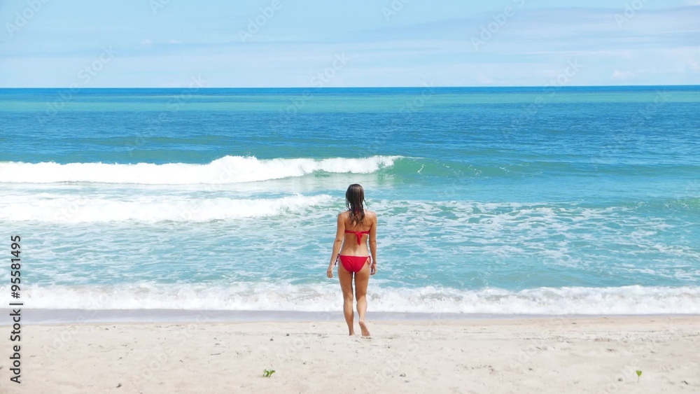 Beautiful Caucasian woman in red bikini jokes and relaxing on the beach with white sand. New Year in jungle sea view and sunlight. Holiday in tropics. Beautiful Caucasian woman in red bikini jokes and relaxing on the beach with white sand. New Year in jungle sea view and sunlight. Holiday in tropics.
