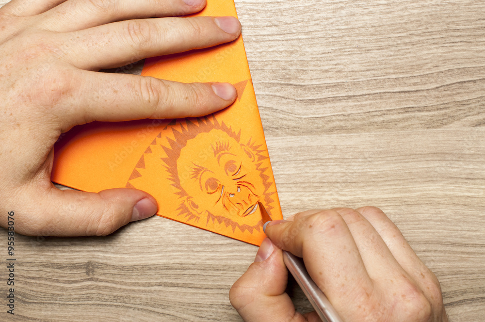 Fototapeta premium Monkey business for monkey`s year. A man carves the snowflake, with monkey face, out of paper