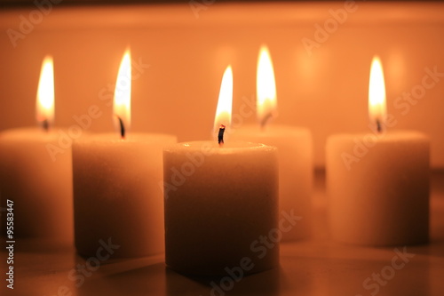 Holiday candles burning on a white background and reflected.