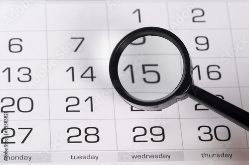 Black magnifying glass over calendar