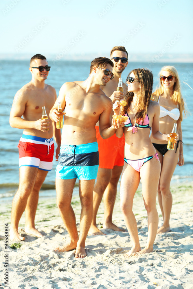 Happy young friends drinking beer at the beach, outdoors Happy young friends drinking beer at the beach, outdoors