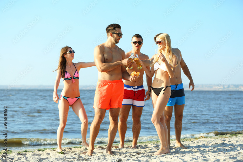 Happy young friends drinking beer at the beach, outdoors Happy young friends drinking beer at the beach, outdoors
