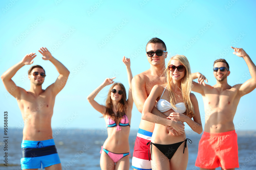 Happy couple and their playful friends relaxing at the beach, outdoors Happy couple and their playful friends relaxing at the beach, outdoors