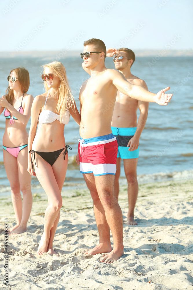 Happy couple and their playful friends relaxing at the beach, outdoors Happy couple and their playful friends relaxing at the beach, outdoors