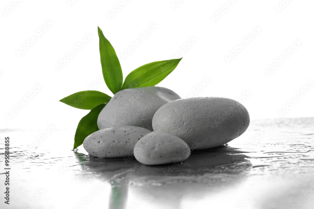 Stack of stones and a green flower on white wet background. Spa relaxation concept Stack of stones and a green flower on white wet background. Spa relaxation concept