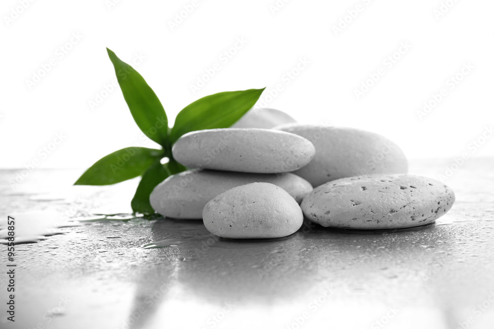Stack of stones and a green flower on white wet background. Spa relaxation concept Stack of stones and a green flower on white wet background. Spa relaxation concept