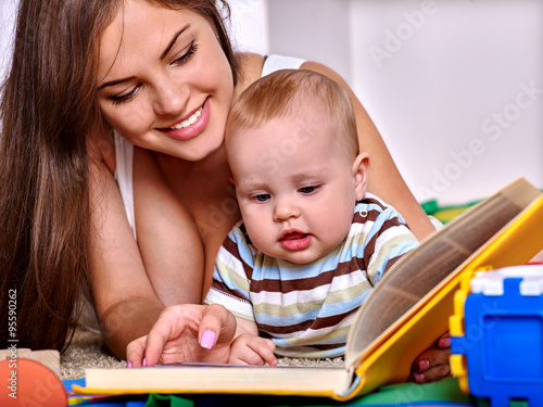 Child with mother reading book at home.