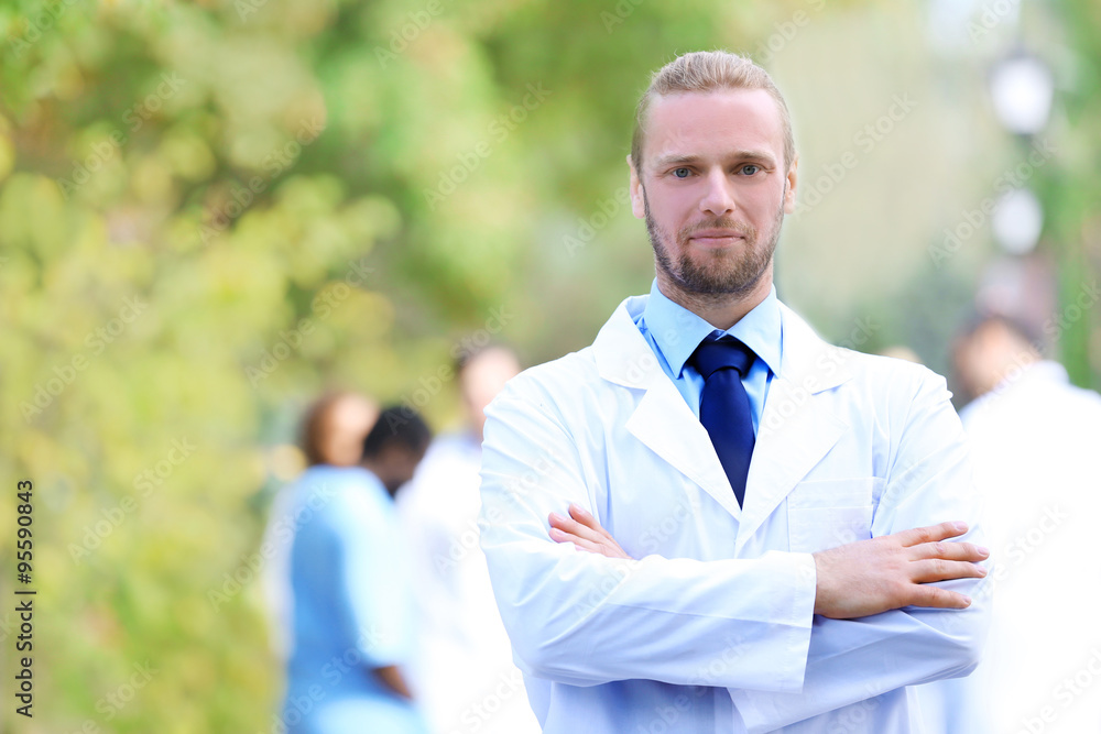 Handsome doctor with medical stuff behind, outdoors Handsome doctor with medical stuff behind, outdoors