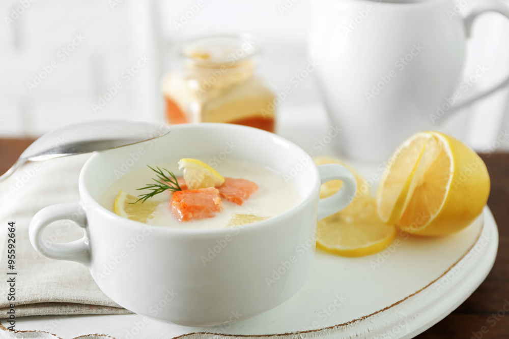 Delicious salmon cream soup with sliced lemon on white tray, close up Delicious salmon cream soup with sliced lemon on white tray, close up