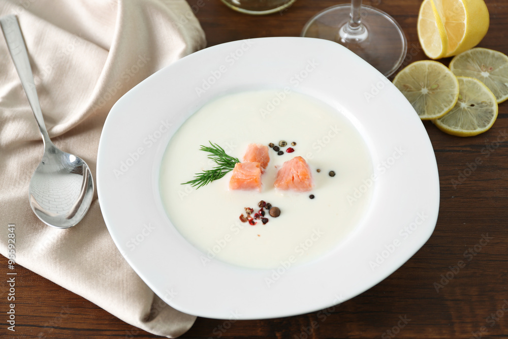 Delicious salmon cream soup with spoon on wooden table, close up Delicious salmon cream soup with spoon on wooden table, close up