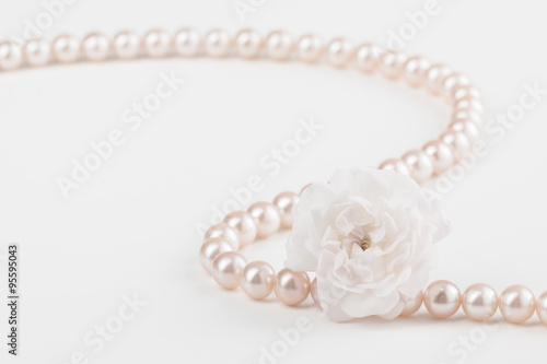 Pearl necklace close up with miniature rose