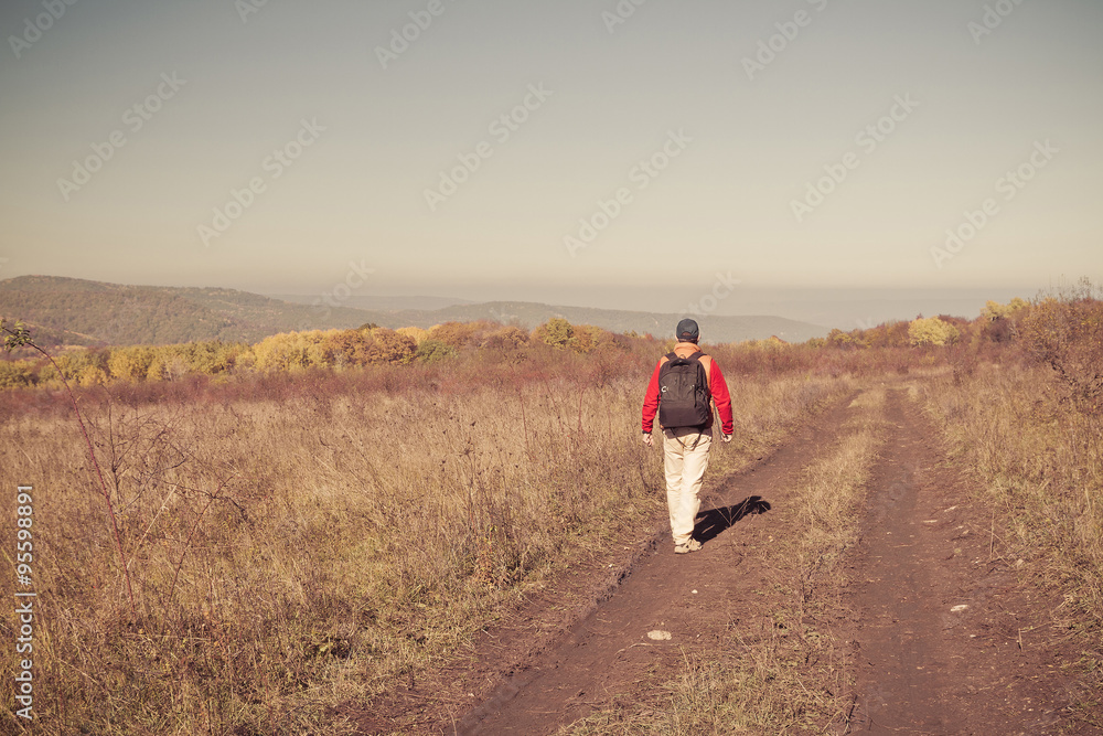 Male tourist with backpack is on a rural road