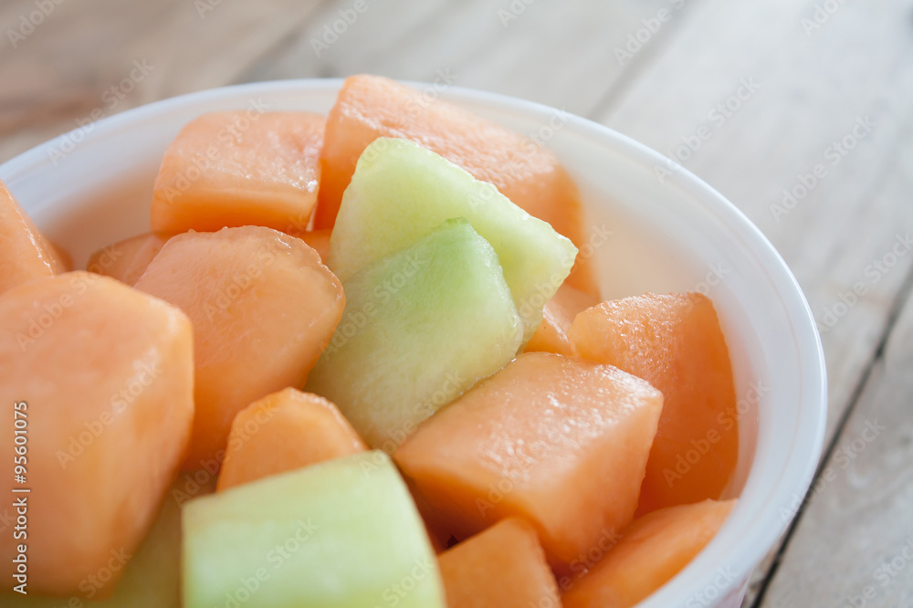 closeup melon slice in white dish with wood table background closeup melon slice in white dish with wood table background