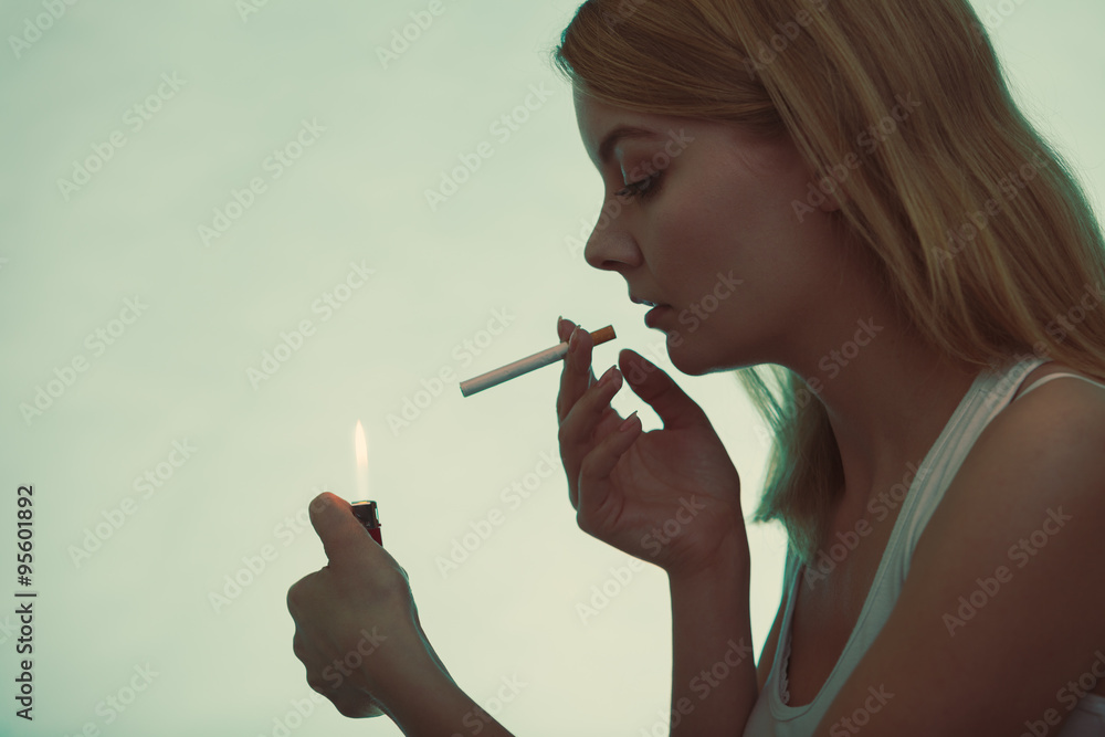 Obraz premium Girl using lighter to light cigarette.