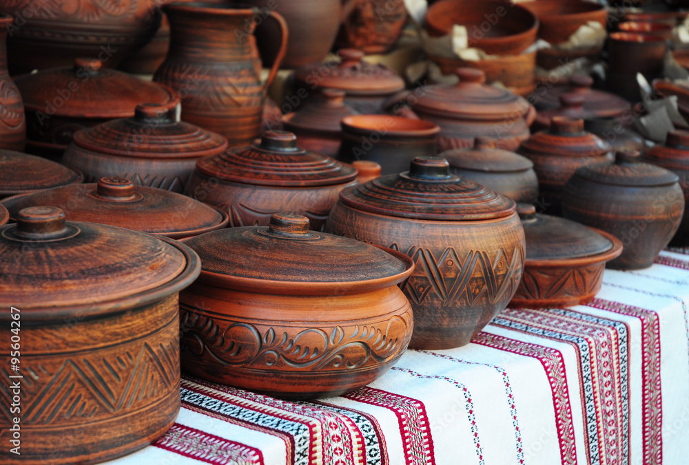 Traditional Ceramic Jugs on Decorative Towel. Showcase of Handmade Ukraine Ceramic Pottery in a Roadside Market with Ceramic Pots and Clay Plates Outdoors.
