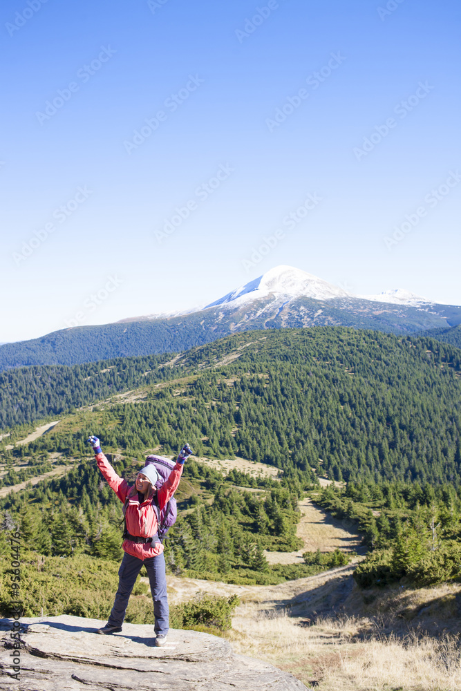 A girl stands on top of a mountain.