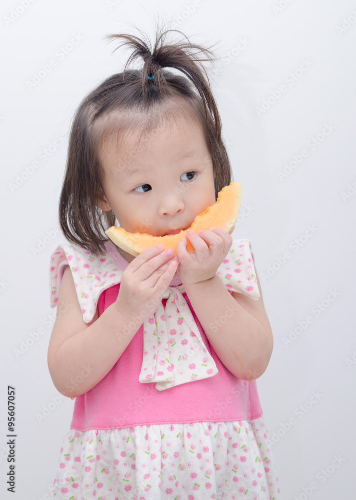 Little Asian girl eating melon over white background Little Asian girl eating melon over white background