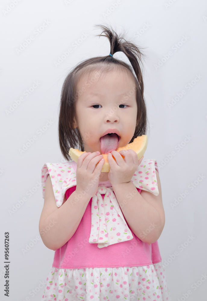 Little Asian girl eating melon over white background Little Asian girl eating melon over white background