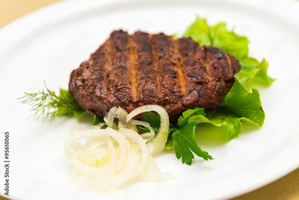 Closeup view of fried marbled meat with lettuce and onion rings Closeup view of fried marbled meat with lettuce and onion rings