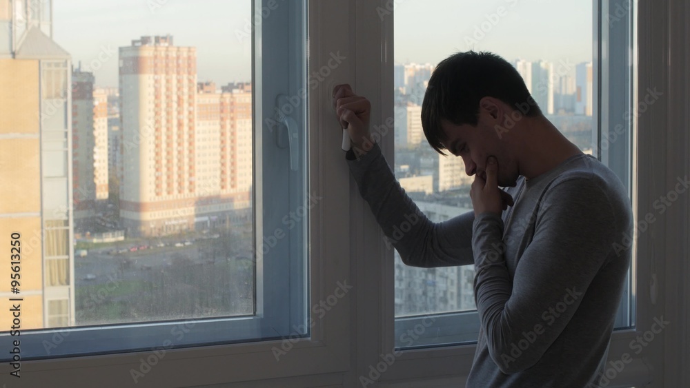 Worried man stand and crying near window Worried man stand and crying near window