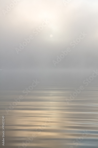 Morning sun through fog at lake
