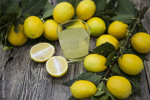 Fresh juicy lemons and a glass of homemade lemonade on a wooden background