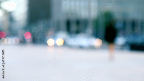 anonymous man walking alone in the street in a blurred out of focus colorful background of urban context photo