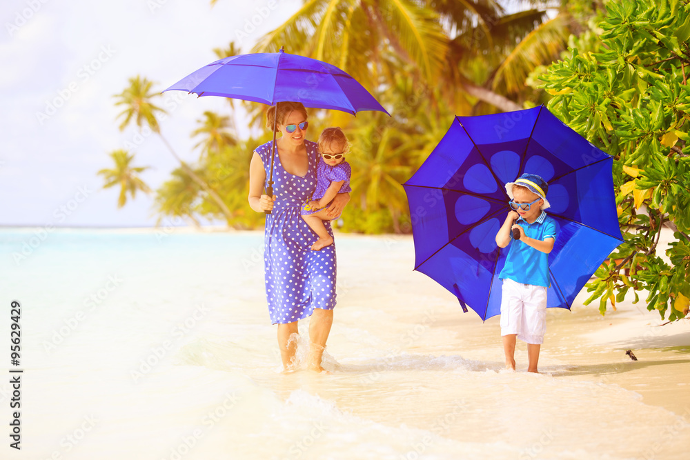 mother and two kids at beach with umbrellas