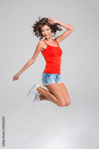 Curly happy young woman jumping and smiling