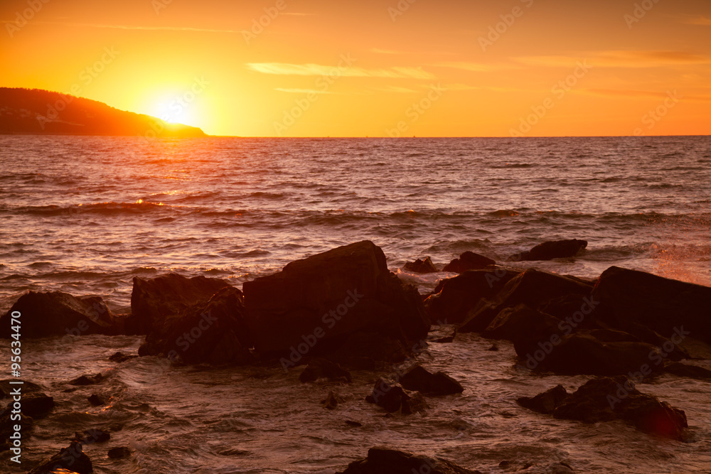 Coastal stones and sea water at sunset, summer