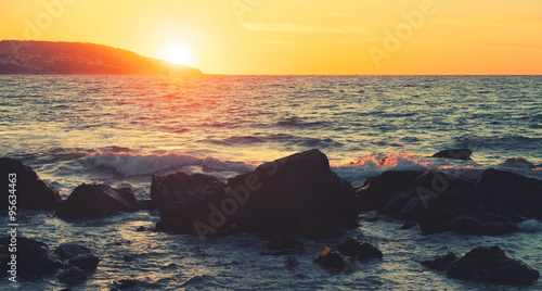 Coastal stones and sea water at summer sunset
