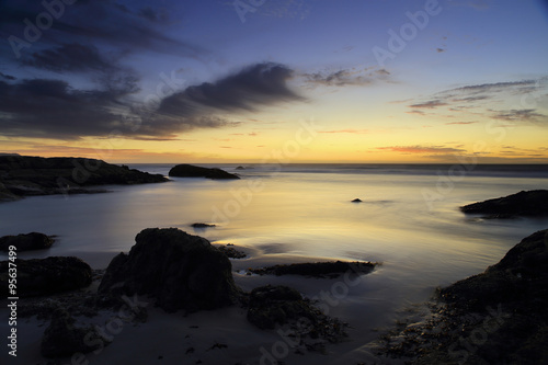 Blurred water / A sunset on the coast of the Atlantic Ocean, South Africa, with the blue cloudy sky in the background and blurry water and rocks in the foreground