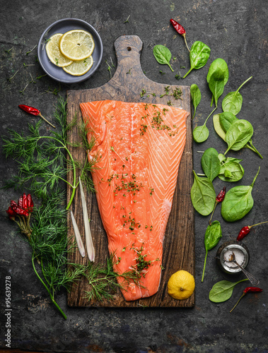 Perfect salmon fillet on rustic cutting board with fresh ingredients for tasty cooking