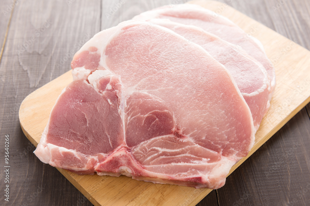 Raw pork chop steak on wooden cutting board Raw pork chop steak on wooden cutting board
