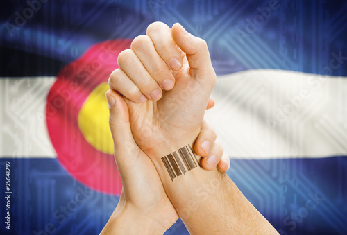 Barcode ID number on wrist and USA states flags on background - Colorado photo